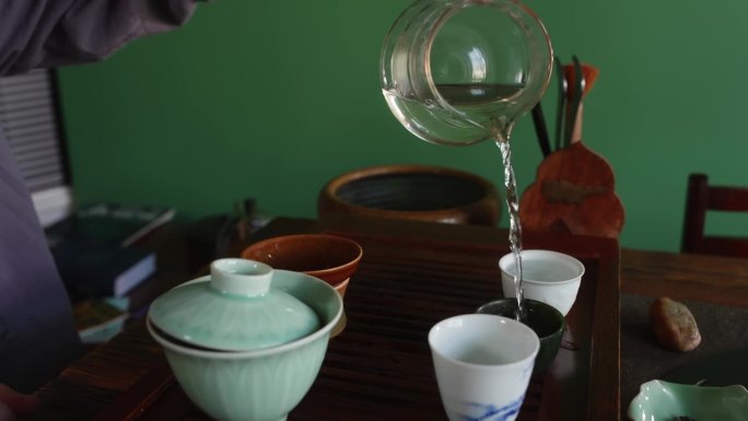 茶艺师在茶道上把热水从玻璃壶倒到茶杯里。