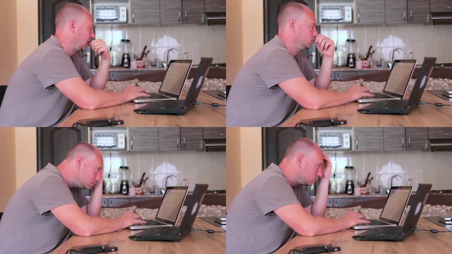 在厨房里神情专注的白人男子坐在笔记本电脑前用键盘打字