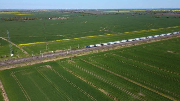 现代高速客运列车由铁路行驶，穿过有农用地的农村