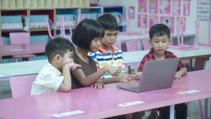 一群亚洲学生和他们的老师在教室里上笔记本电脑课。