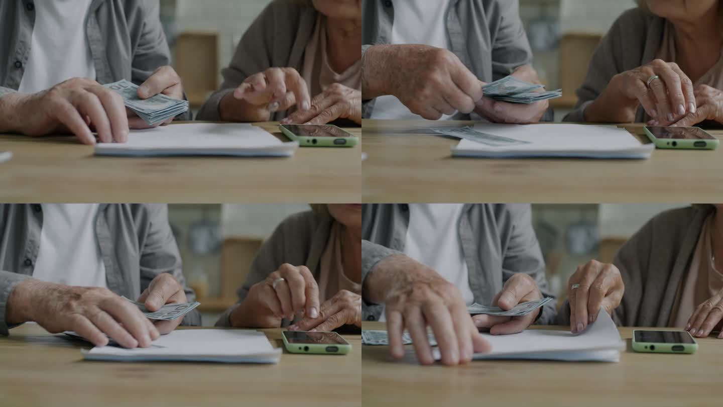 老年夫妇的手特写，在家里的桌子上用智能手机计算付款，拿着钱