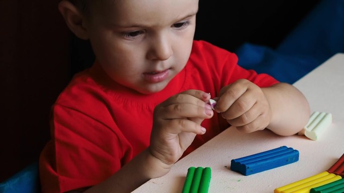 一个小男孩用彩色橡皮泥雕刻人物的视频