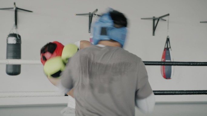 年轻的运动员和拳击手在现代体育馆里一起训练，戴着手套和头盔保护身体