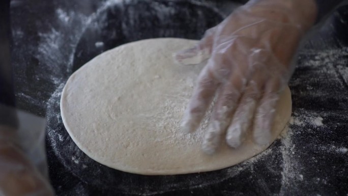 意大利厨师准备披萨面团，在石桌上擀面，开始制作披萨