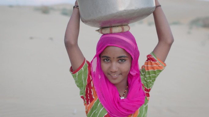 印度沙漠村庄里，年轻女孩从井里打水