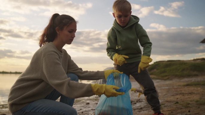 孩子和家长在河边收集塑料垃圾，清洁自然