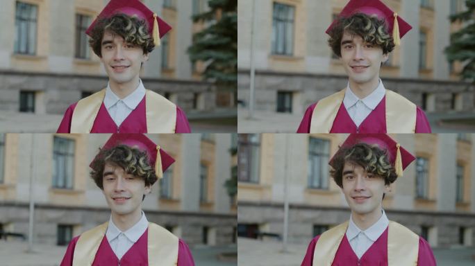 慢动作肖像，雄心勃勃的家伙大学毕业生站在校园里穿着长袍和砂浆板微笑