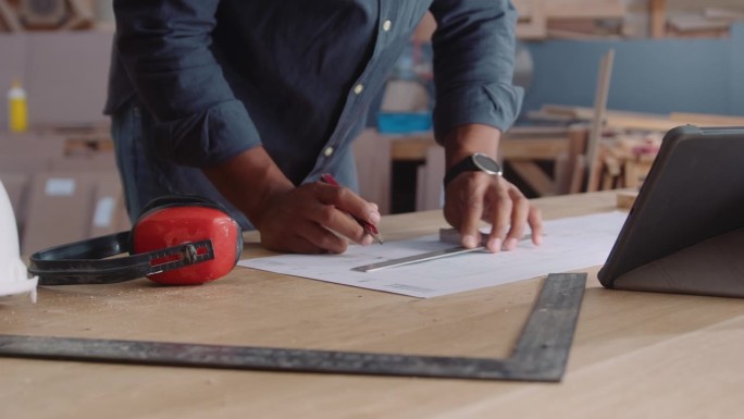 在木工工厂工作的年轻人一边使用工具一边在纸上写字的特写