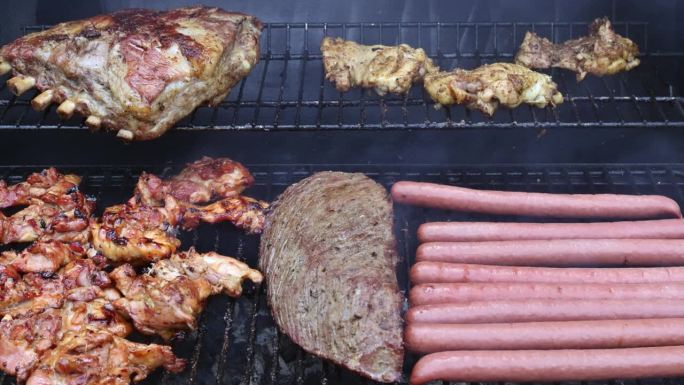 不同种类的肉，牛肉，烤猪肉，鸡肉，香肠在烧烤架上烹饪