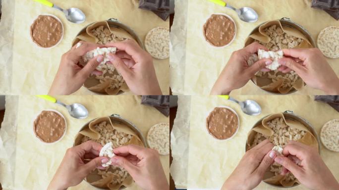 特写:女性双手在蛋糕模具上打碎膨化的米面包。俯视图的女人手压碎饮食脆圆米华夫饼烘烤巧克力和咸焦糖。碾