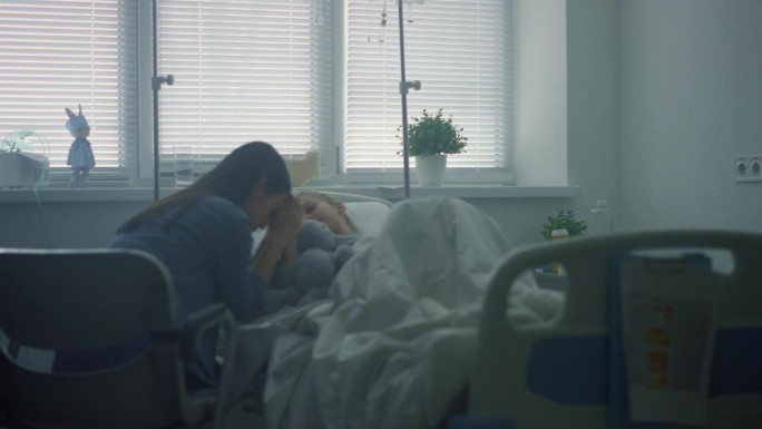 母亲担心生病的孩子在诊所治疗后。重病的孩子躺在床上。