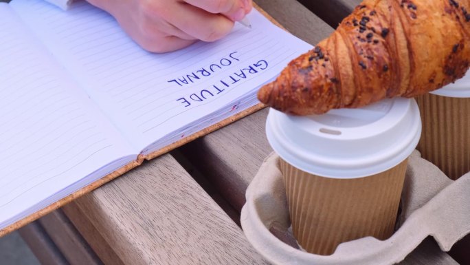 年轻的学生在公园里用笔记本学习。喝咖啡，吃牛角面包。写感恩日记，自我反省，自我发现