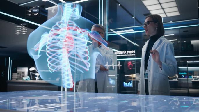 两名生物工程师在未来实验室中使用计算机驱动的人体胸部动画视觉特效全息图。白人男性和女性致力于创新心脏