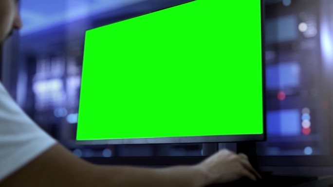 工程师在绿色屏幕的电脑上工作。在后台，有一个生产大厅，一个在技术、机械或IT行业的设计设施中工作的模