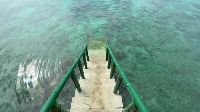 通往大海的楼梯配有竹制扶手。清澈的海水，底部有珊瑚。