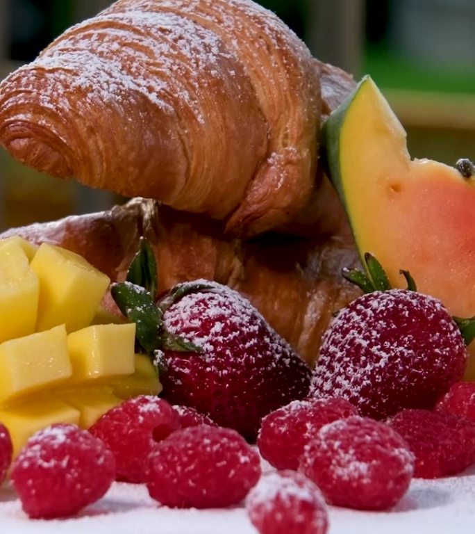 水果背景，刚烤的牛角面包和托盘上的水果托盘，一个不寻常的创意早餐与咖啡。概念:早上好，早餐，美味，慢