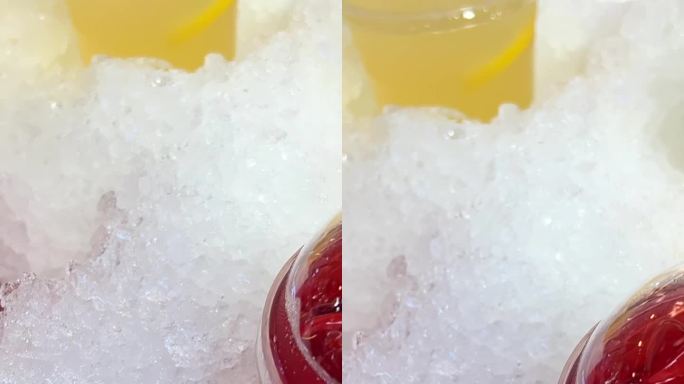 在市场上出售的黄色和红色的塑料杯饮料放在冰樱桃或覆盆子饮料和柠檬慕斯方便的人造雪，防止饮料变冷