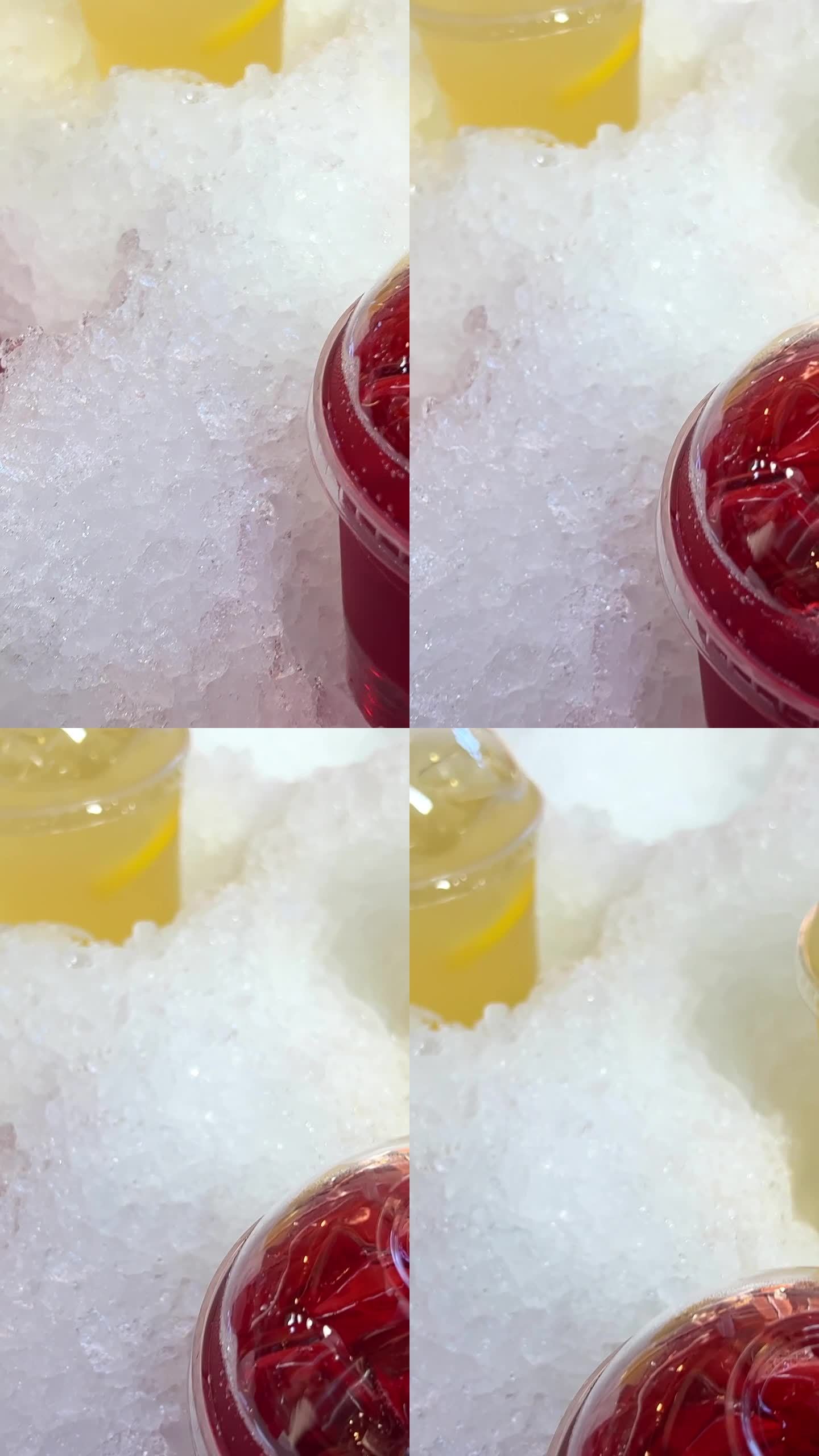在市场上出售的黄色和红色的塑料杯饮料放在冰樱桃或覆盆子饮料和柠檬慕斯方便的人造雪，防止饮料变冷