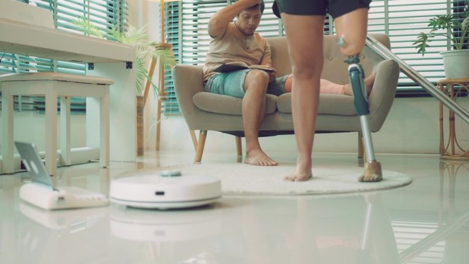 机器人真空吸尘器:亚洲残疾夫妇在家锻炼，营造整洁的环境