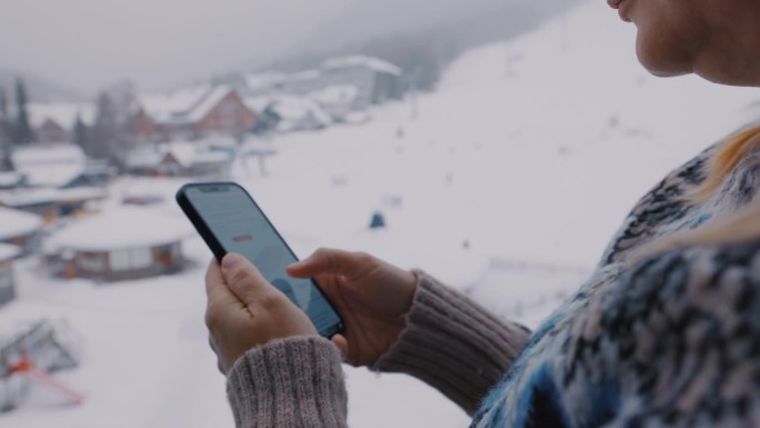 一位女士在滑雪道上使用她的智能手机