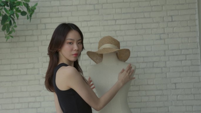 女时装设计师精心为人体模特戴上一顶帽子