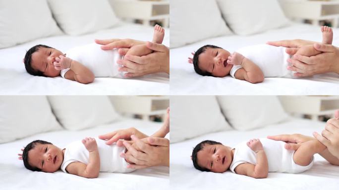 一个皮肤白皙的女人的妈妈的手轻轻地抚摸着肚子或按摩着一个刚出生的非洲裔美国婴儿，一个刚睡醒或睡着的小