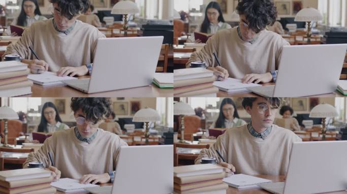 年轻人的肖像勤奋的学生在图书馆学习使用笔记本电脑打字和记笔记