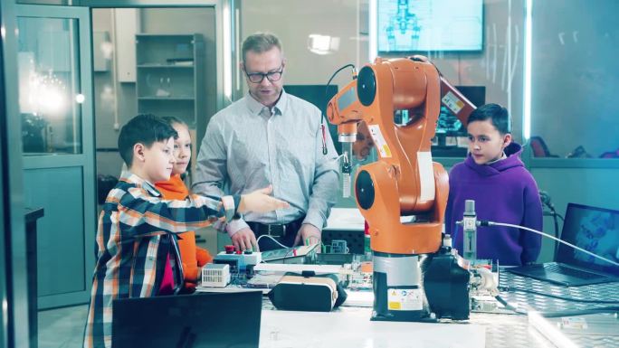 在学校实验室里，老师和学生一起和机器人一起工作