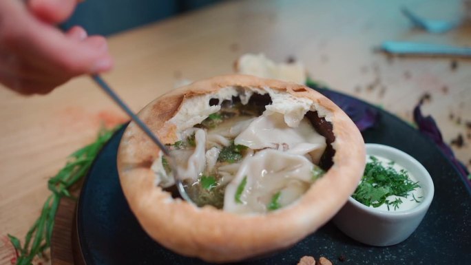 用勺子在可食用的生面团碗里用金卡利和绿欧芹喝汤