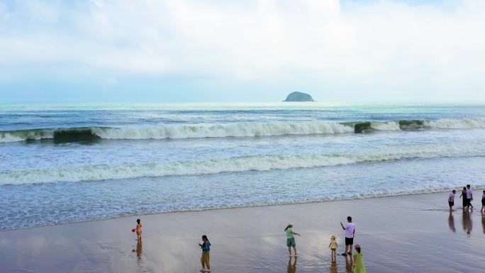 海浪拍打沙滩海边游玩的人浪花朵朵