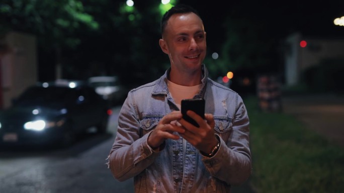 帅哥在夏夜的城市街道上看手机
