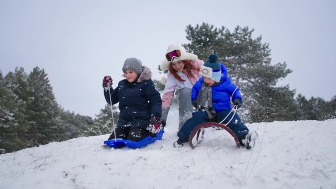 寒假活跃，妈妈带着孩子在森林里玩雪橇下山，少妇拍手叫好