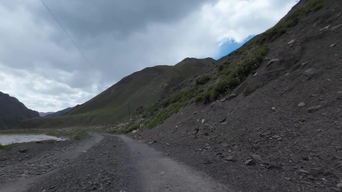 沿着山河行驶在土石路上。汽车的观点