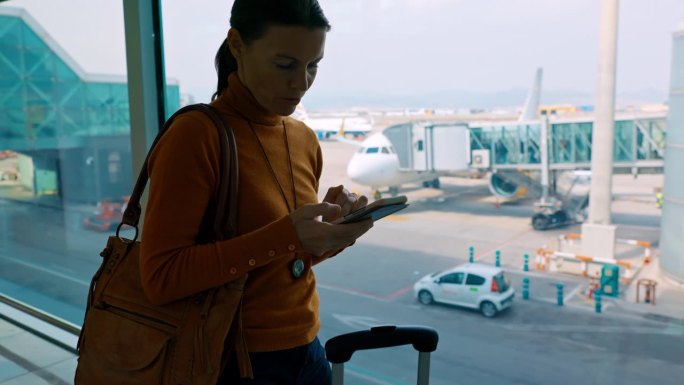 MS Woman在机场候机时使用智能手机