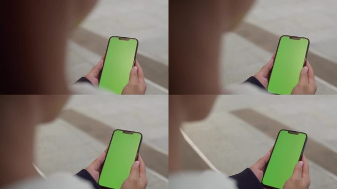 一名女子在城市的街道上使用绿色色度键屏的智能手机。