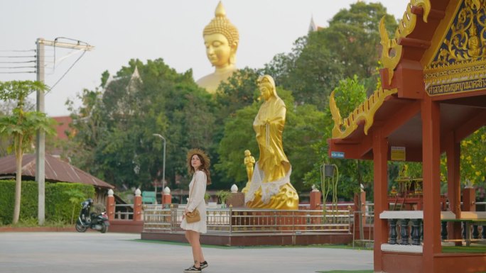 一名女子在曼谷的金佛背景下走在寺庙里