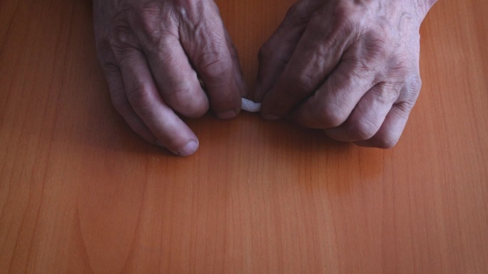 一个老人用过滤嘴折断香烟的手。放弃坏习惯，这位退休老人戒烟了。健康理念。阻止尼古丁