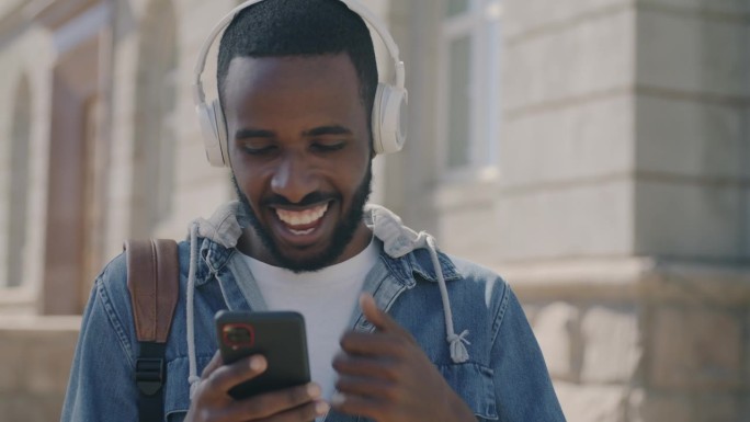 非洲裔美国人在城市里唱歌跳舞，戴着耳机听音乐，用智能手机