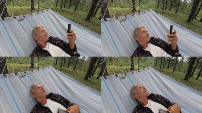 老人在吊床上休息，查看智能手机