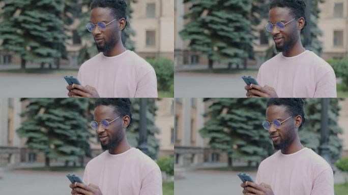 兴高采烈的非洲裔美国人站在城市街道上用智能手机发短信，忙着在线交流