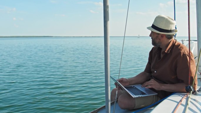 男子在帆船上旅行时使用笔记本电脑