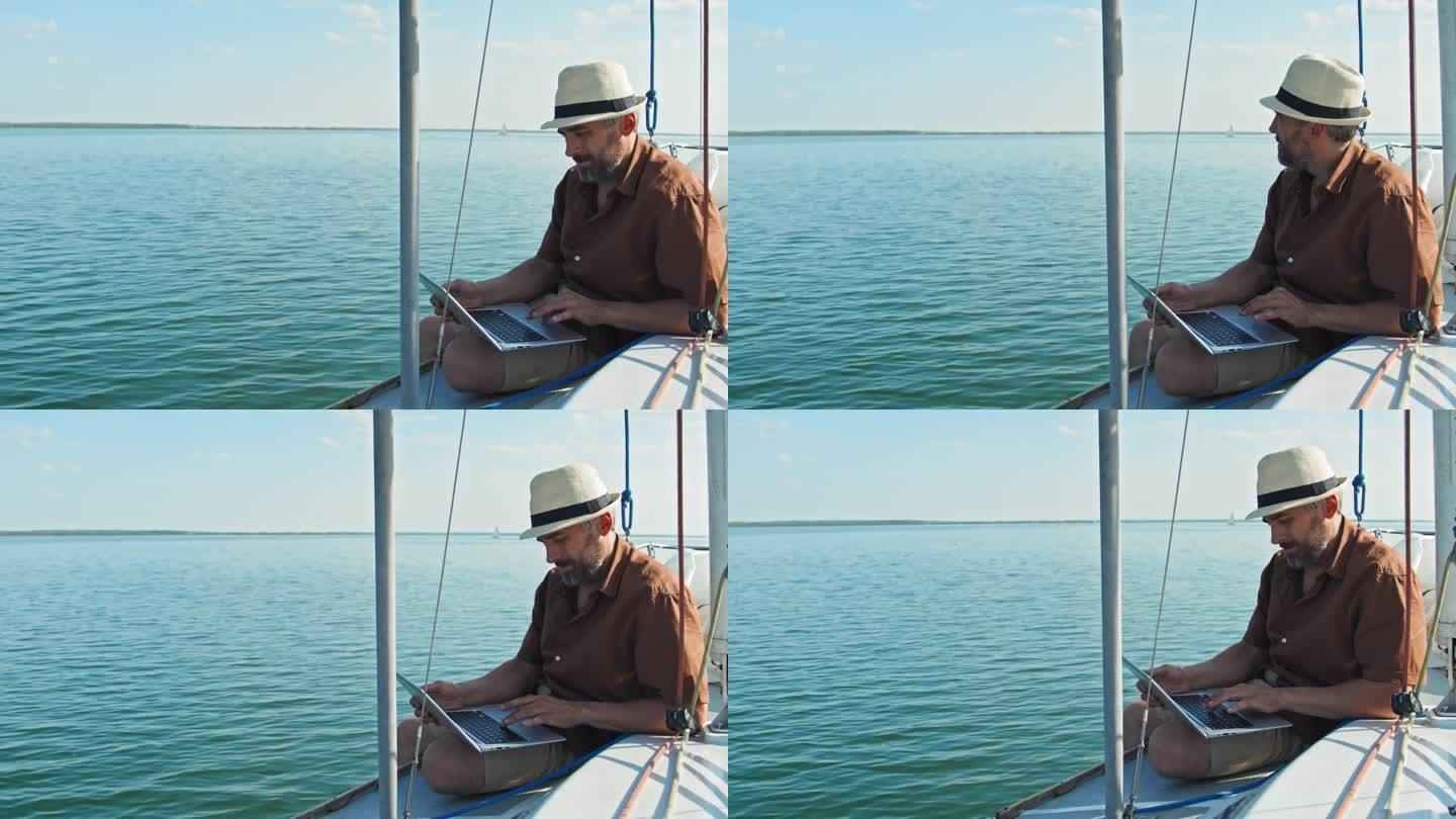 男子在帆船上旅行时使用笔记本电脑
