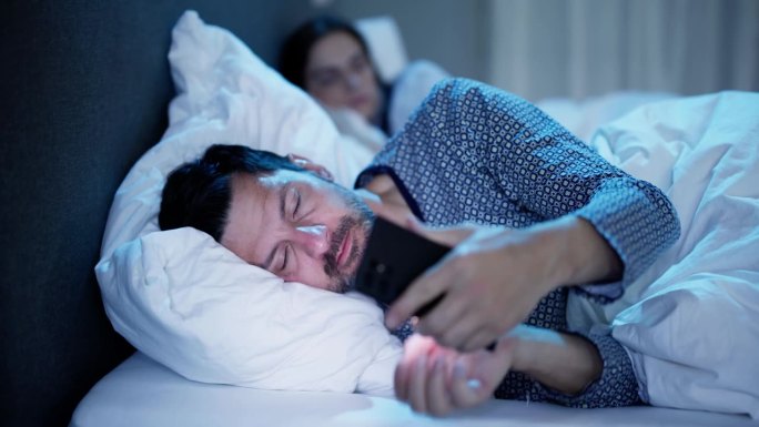 当妻子坐在床上时，年轻人在玩手机
