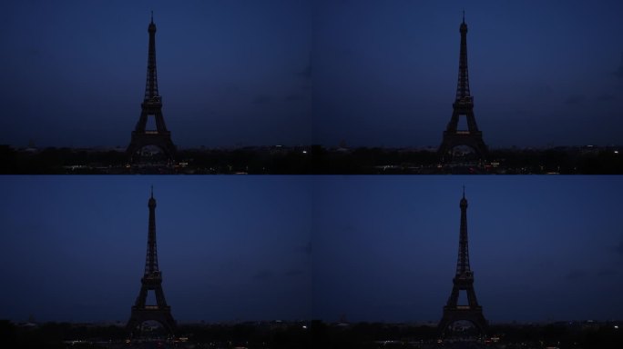 远处没有灯光的埃菲尔铁塔的剪影映衬着黑暗的天空。巴黎的标志性建筑，法国著名的历史地标。