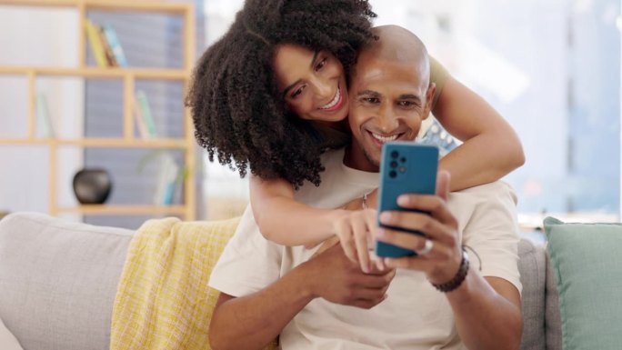 夫妻，在沙发上拥抱和打电话，在家里微笑，在客厅玩社交媒体或上网。幸福，手机和男女拥抱，依偎或拥抱时，