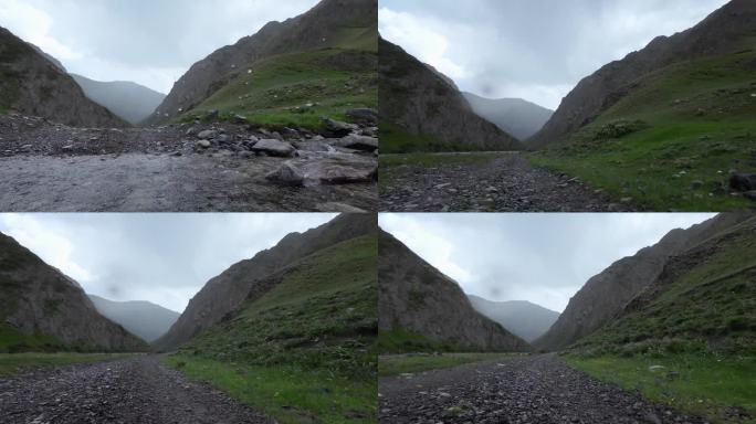 雨中驾车在泥泞的岩石路上穿过山谷。汽车的观点