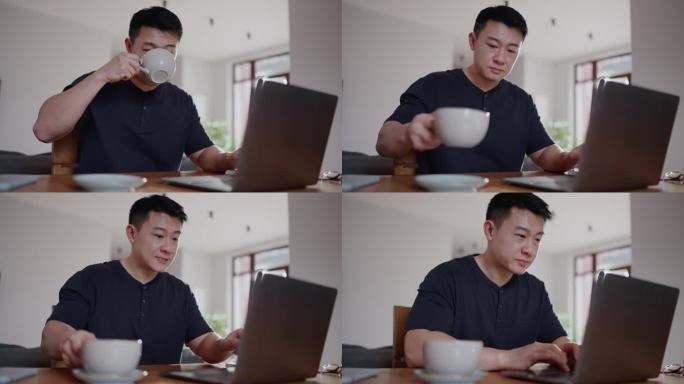 帅气的亚洲男人在家里喝咖啡，用笔记本电脑工作