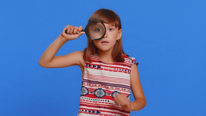 童女拿着放大镜，用大而滑稽的眼睛看着镜头，分析着