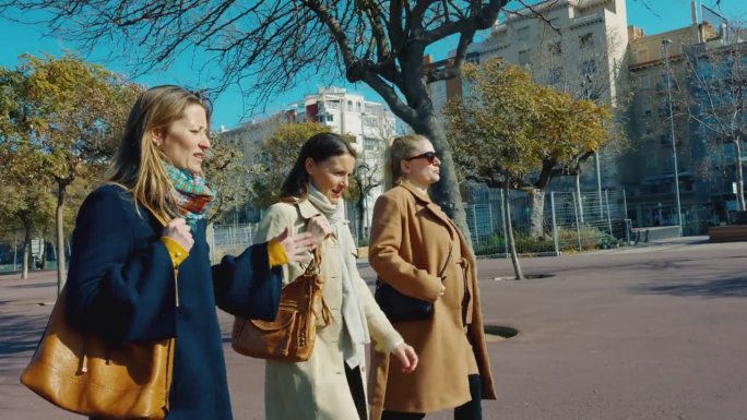 在巴塞罗那，三个女性朋友一边走在人行道上一边聊天