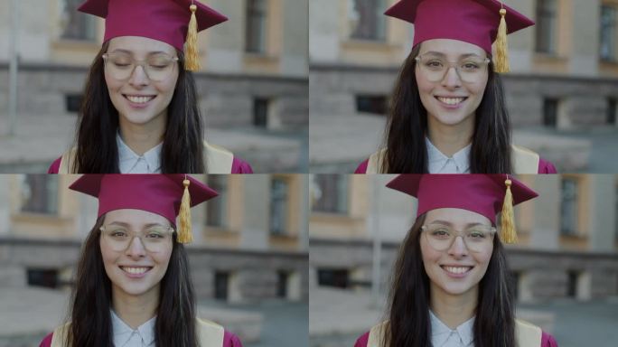 快乐的年轻女大学毕业生的肖像，戴着帽子，穿着长袍，在校园里微笑